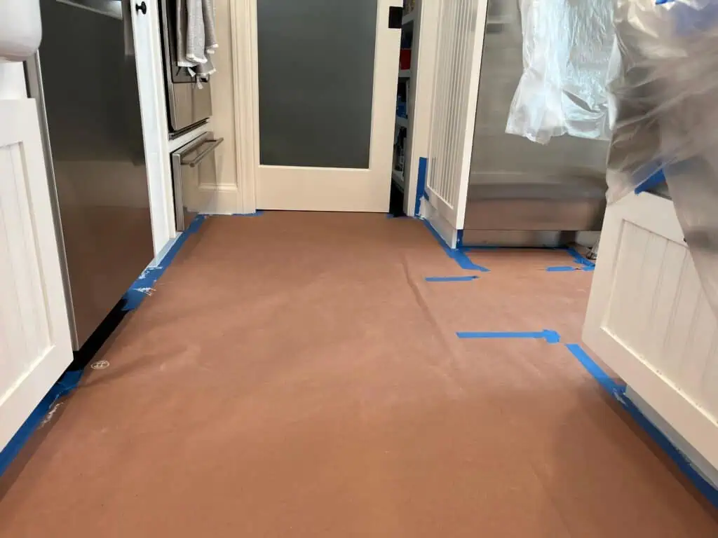 Kitchen floor covered with protective paper and painter's tape for painting.