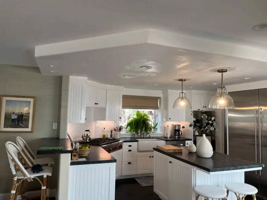 Bright modern kitchen with white cabinets and black countertops, stainless steel appliances, and a p.