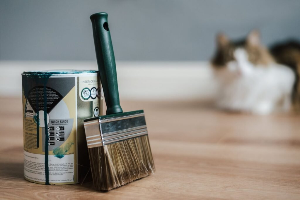 Illustrative photo: a paintbrush and paint can on a protected project floor
